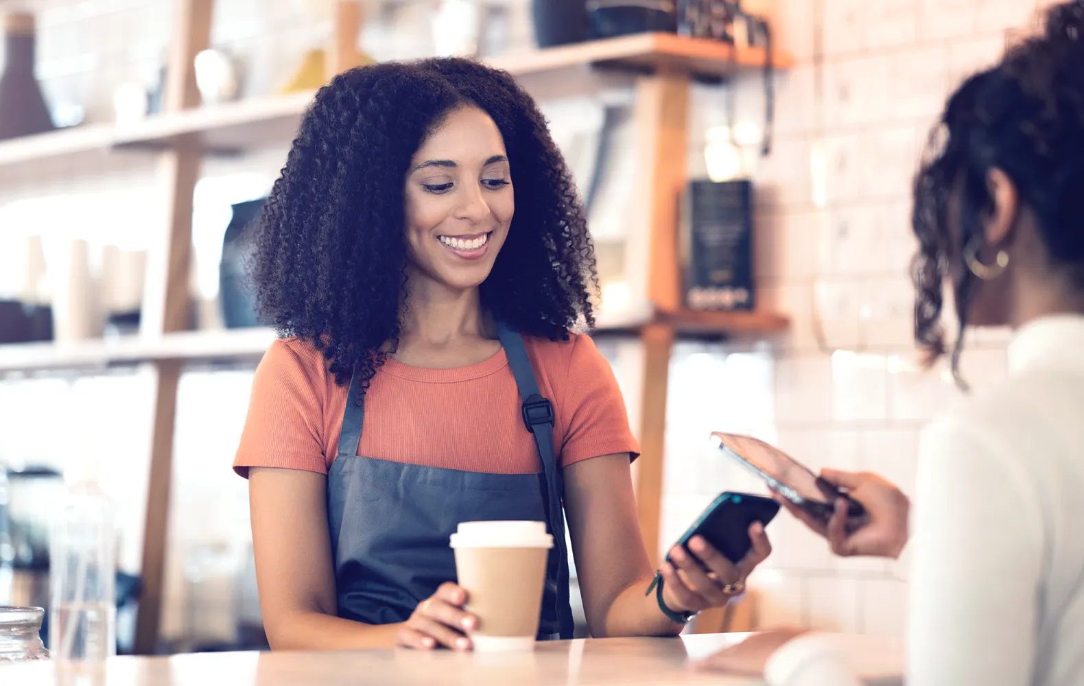 SMB_Women paying with phone at coffee shop_SoftPOS.png